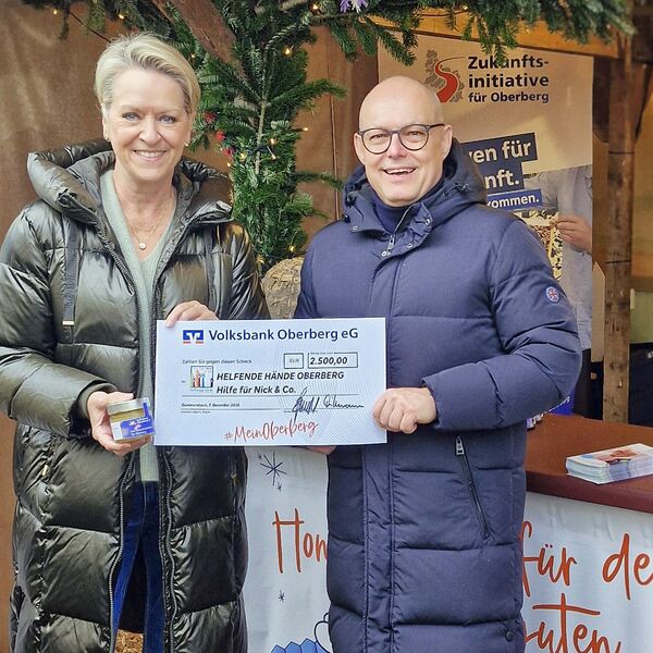 Volksbank Oberberg --- Vorstandsmitglied Jörn Richling überreicht Bettina Hühn im Winterdorf Gummersbach den symbolischen Spendenscheck über 2.500 Euro.